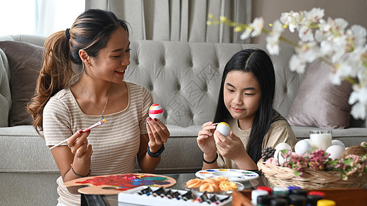 微笑的妈妈和女儿喜欢在客厅一起画复活节鸡蛋 在起居室图片