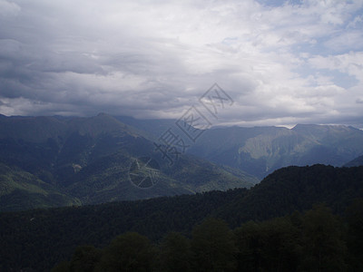 一片全景的山地景观 其山谷和森林山峰在高覆云天下荒野爬坡道顶峰旅游山脉石头木头地平线场地岩石图片