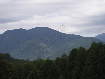 一片全景的山地景观 其山谷和森林山峰在高覆云天下爬坡道旅游冒险房子地平线石头蓝色旅行农村远足图片