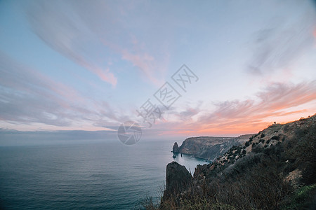 海上的红色燃烧日落与岩石火山悬崖 抽象自然夏季或春季海洋背景 金色温暖水面上的小波浪与来自太阳的散景灯调子海浪假期阳光火花季节蓝图片