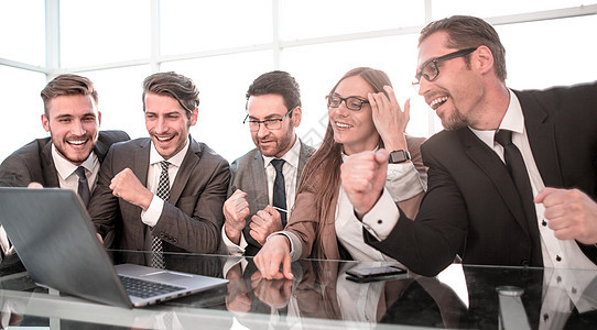 快乐的同事在办公桌上 举起手来手势管理人员套装笔记本合作职场幸福项目优胜者成人图片