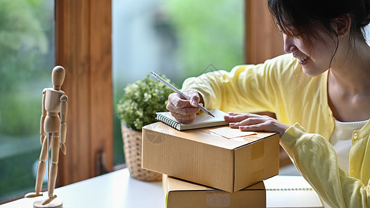 重点青年妇女在线主线销售者在纸板盒上书写地址 同时准备送货产品包装箱图片