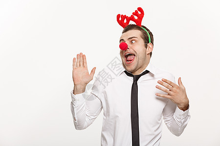 圣诞概念     穿着驯鹿发带的英俊商行男子 在面部表情上滑稽服装小丑男人男性工人派对商业企业商务经理图片