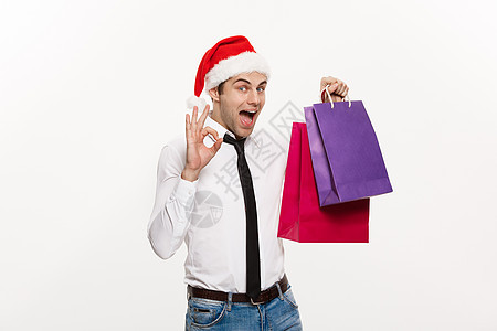 圣诞节概念英俊的商务人士庆祝圣诞快乐和新年快乐戴圣诞老人帽子和圣诞老人红色大袋子礼物盒庆典零售礼品盒消费者假期展示购物狂商务男人图片
