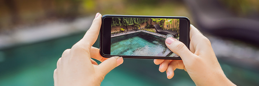 手持电话在酒店游泳池的背景上 屏幕上的照相机 近距离手持智能手机拍摄暑假横幅 长格式图片