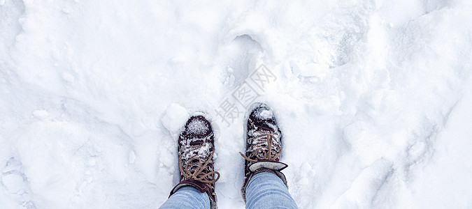 旗帜与腿在勃艮第靴子和蓝色牛仔裤在雪地里 雪地上的脚印 冬季景观图片