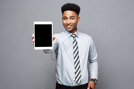 商业概念     英俊 专业的非洲商务人士向客户展示数字平板电脑 快乐软垫微笑屏幕成人监视器手指男人工作商务工作室图片