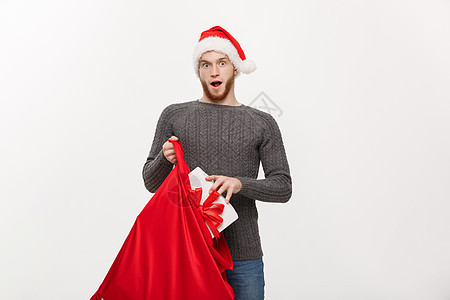 圣诞概念  快乐的长胡子年轻男人在圣塔袋子里 兴奋地拿着大礼物解雇新年季节传统假期胡须松树老人男性盒子图片
