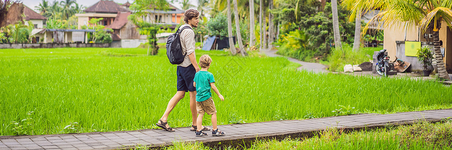 乌米粽在印度尼西亚巴厘岛著名火山的背景下 爸爸和儿子在美丽的水稻梯田上旅行 带着孩子旅行的概念横幅 长格式背景
