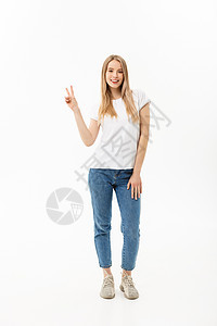 一位快乐的年轻女子全长的肖像 她站立并展示和平姿态 两只手在白背景上被孤立微笑成人胜利喜悦手指成就女孩手势工人成功图片