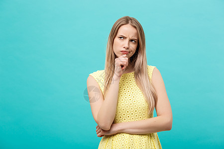 思考年轻自信的穿黄色礼服的女人 在蓝背景中与世隔绝女士女孩快乐思维成功黑发工作室头发商业裙子图片