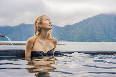 地热温泉 在温泉游泳池中与湖对面放松的妇女 温泉概念假期女性成人乐趣观光眼睛火山闲暇水池旅行图片