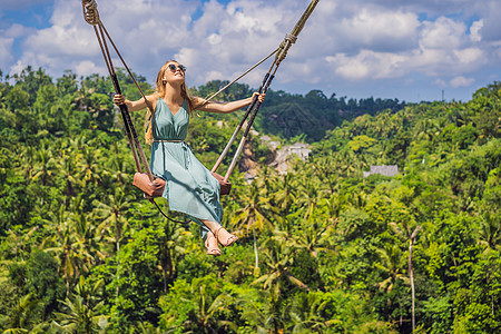年轻女子在印度尼西亚巴厘岛的丛林雨林中荡秋千 在热带摇摆 秋千巴厘岛的潮流闲暇游客棕榈荒野青少年绳索女孩冒险顶峰头发图片