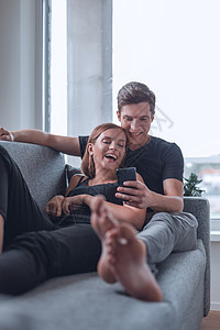 在舒适的客厅里沙发上放轻松的一对可爱的年轻夫妇幸福闲暇工具女性男人女士家庭房子生活技术图片