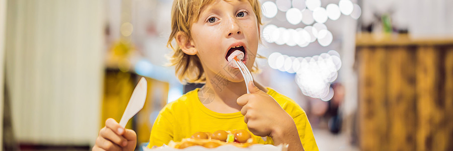 一个小男孩吃甜点华夫饼 果酱加果酱 在咖啡馆 长时间微笑桌子美食乐趣格式孩子童年阳台食物食欲图片