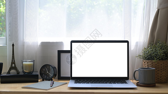 带白色屏幕 陶瓷植物 咖啡杯和木制桌上的图画框的前端看笔记电脑图片