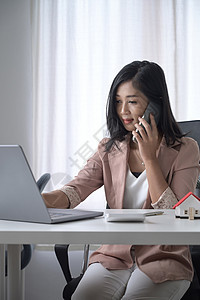 忙碌的女商务人士使用笔记本电脑和移动电话交谈图片