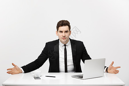 商业概念 年轻商务人士在明亮办公室工作 坐在办公桌前 使用带有严重面部表情的笔记本电脑技术成人专注男人桌子工人领带职场套装职业图片