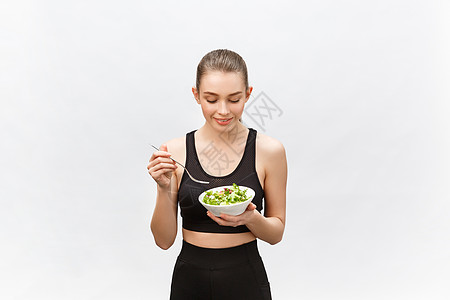 年轻漂亮的运动女郎 在白色背景下吃沙拉喜悦女士成人女孩节食营养微笑女性快乐食物图片