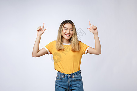 美丽的亚洲年轻女子用愉快的表情 用白色背景来指着她的手指 举起手来商业喜悦女士成人快乐青少年学生微笑裙子学习图片