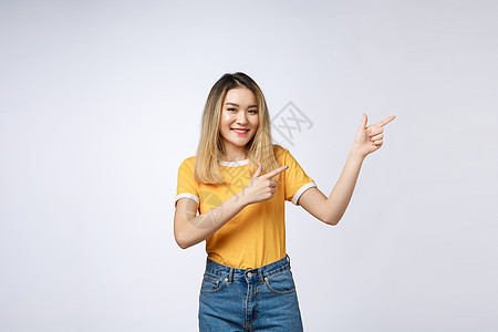 美丽的亚洲年轻女子用愉快的表情 用白色背景来指着她的手指 举起手来喜悦成人女士裙子商业快乐青少年学习微笑女孩图片