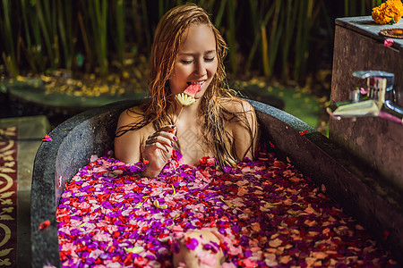 有魅力的年轻女人在沐浴着热带花卉和芳香油的花瓣 用于皮肤再生的水疗护理 Spa 沙龙的迷人女人 放松在有花瓣的浴缸的女孩 奢华花图片