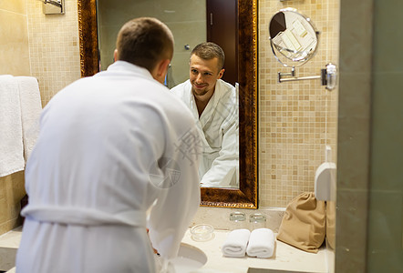 一个男人穿着白色大衣微笑 早上在浴室的镜子里看着他自己 他笑了起来图片