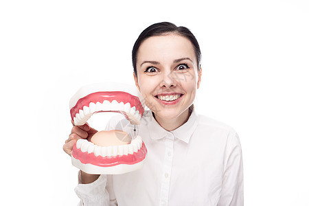 穿着白衬衫的女牙医长着大下巴 手上有牙齿 白色背景图片