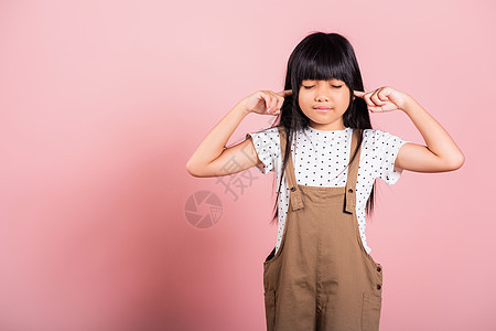 10岁的亚洲小孩用手指和眼睛闭上耳朵 闭着耳朵孩子粉色学校孩子们工作室女士头发青春期鬼脸噪音图片