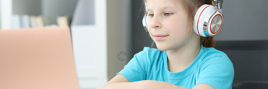 一个持耳机的学生女孩坐在笔记本电脑前图片