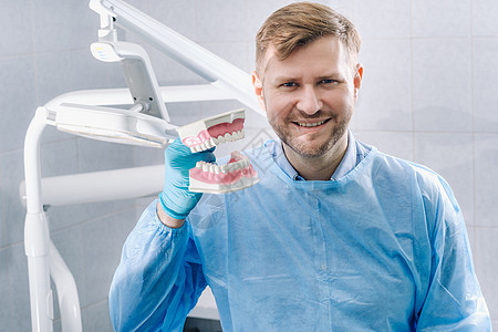 牙齿和牙刷在牙医手上的人体下巴模型以及男人职业卫生治疗师医院药品牙科乳胶蓝色手套图片