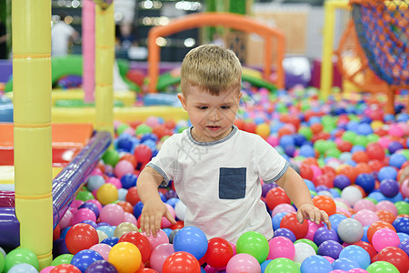 一个男孩在一个干燥的滑板池里 和塑料球一起在游戏中心玩耍图片