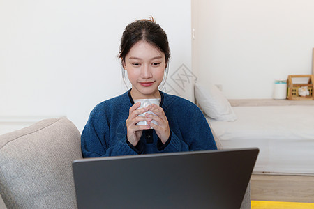 使用笔记本电脑的社交媒体来描绘亚洲年轻女性的肖像 生活方式 网上购物 沙发上放松房间家具长椅喜悦微笑休息室座位窗户享受公寓图片