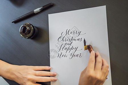 圣诞快乐 新年快乐 书法家年轻女子在白纸上写下短语 题写装饰字母 书法 平面设计 刻字 手写 创作概念女孩卡片墨水新年教育写作女图片