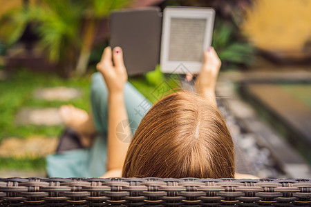 女人在花园的甲板椅子上看电子书成人触摸屏休息小说读者电脑技术女性公园互联网图片