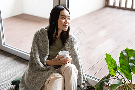 看着窗外满脸梦幻的面孔 喝早咖啡和坐在家院子旁边的笑容的女性房子女孩感染鼻子毯子杯子肺炎发烧互联网温度图片