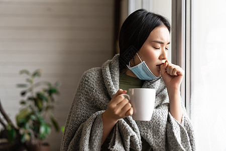 身戴着医疗面罩的生病的亚洲女孩站在窗边 渴望外出 被隔离 患19岁或感冒病肺炎痛苦杯子窗户发烧毯子流感感染房子疾病图片