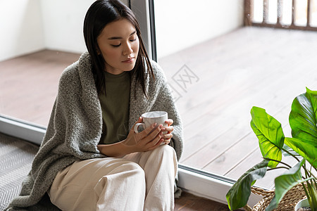 坐在阳台附近的地板上 看着茶杯深思熟虑的茶杯保健房子女孩鼻子发烧疾病女性互联网心碎温度图片