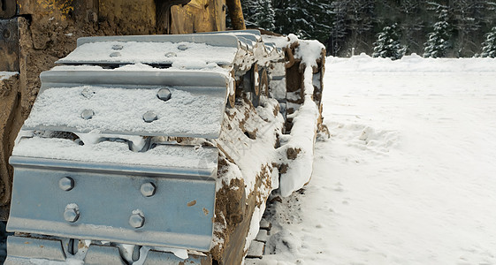 冬天 推土机拖拉机的金属履带清除了道路上的积雪 在寒冷的日子里 冬天有一辆黄色的推土机装载机暴风雪机器搬运工挖掘机车辆机械打扫土图片