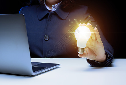 一个女人的手拿着一个灯泡 通过想法和灵感来创新的概念 通过寻找新的活动领域 优化业务发展图片