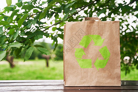 空白纸袋站在一张木制桌子上 以绿叶为背景广告营销购物柜台销售商业回收展示包装食物图片