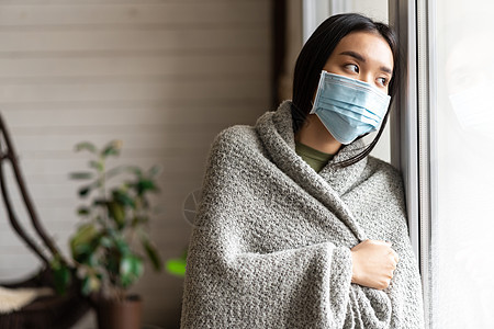 身戴着医疗面罩的生病的亚洲女孩站在窗边 渴望外出 被隔离 患19岁或感冒病窗户女性房子流感痛苦感染心碎疾病互联网毯子图片