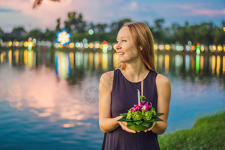 一位女游客手里拿着水灯 准备下水 节 人们购买鲜花和蜡烛点燃并漂浮在水上庆祝泰国的节女孩佛教徒女士旅行女神宗教裙子假期微笑节日图片