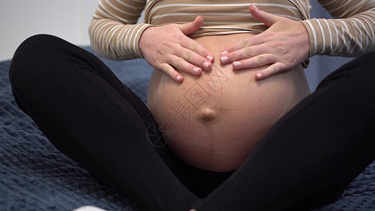 年轻孕妇肚子上有涂片霜 卧室里的女孩在床头缝合中图片