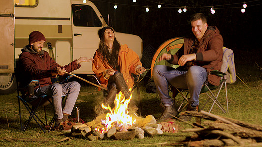 胡子人跟朋友说一个有趣的笑话 在营火周围火焰露营灯泡椅子乐趣房车露营者复古团体胡子图片
