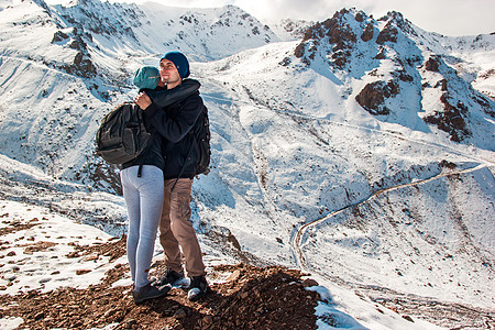 一位年轻男子在雪山背景下拥抱妻子 在山上度假 (笑声)图片