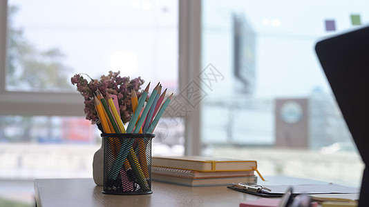 在明亮办公室的木制桌子上 特写铅笔架 书本和笔记本电脑图片