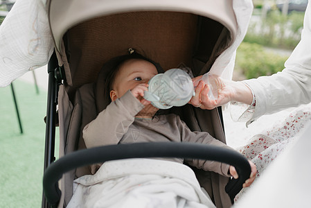 婴儿车里的婴儿正喝着瓶子里的水图片