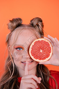 漂亮的补间女孩在橙色与孤立在橙色背景上的葡萄柚 热带柑橘类水果 葡萄柚片 橙色时尚化妆 青少年肖像眼睛营养化妆品果汁柚子护理食物图片