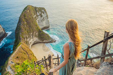 家庭度假生活方式 幸福妇女站在一旁 看看高悬崖下美丽的海滩 巴厘旅游目的地 努沙佩尼达岛最受欢迎的参观地点班台岩石快乐女性海景海图片